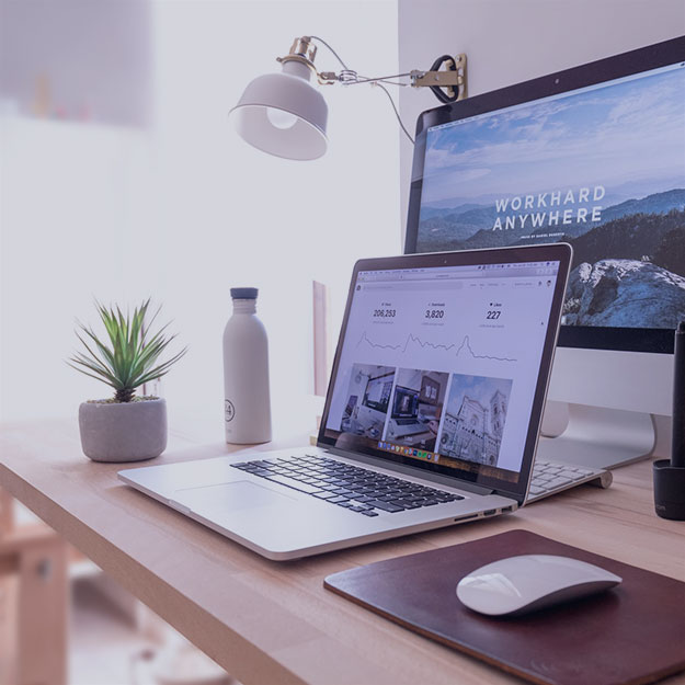 Laptop and mouse on a desk in front of a screen